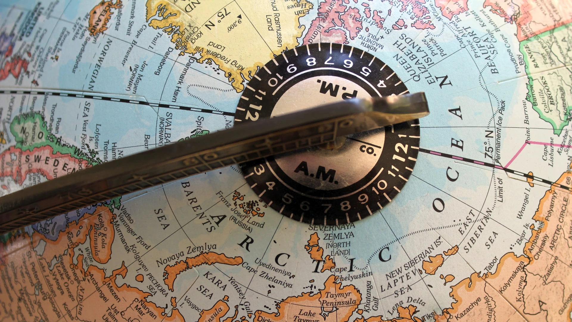 Close-up van een antieke geografische wereldbol gericht op het noordpoolgebied, met een metalen tijdzone-meridiaanring en gradenboog.
