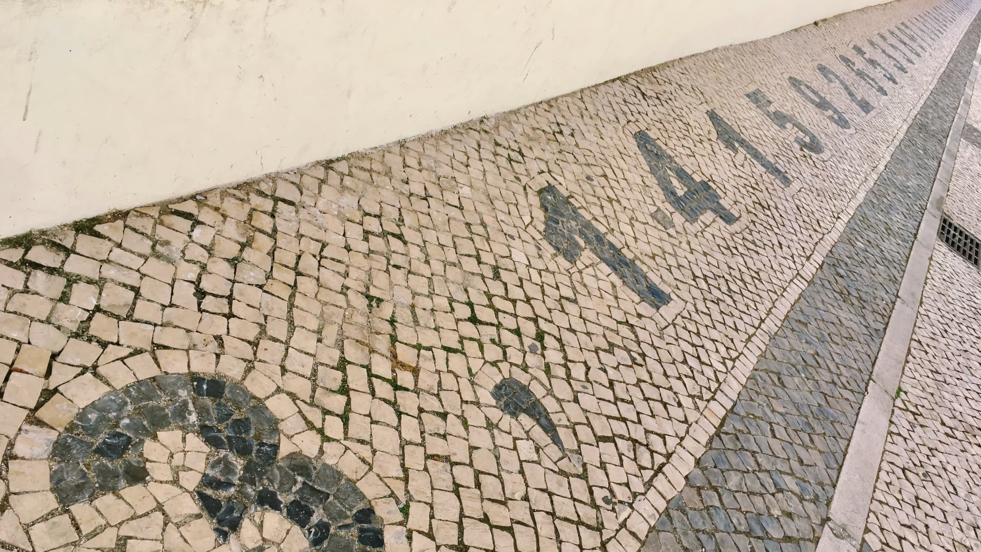 Angled overhead shot of Portuguese pavement (calçada portuguesa) with the inlaid black digits of pi: 3 point 1 4 1 5 9 2.