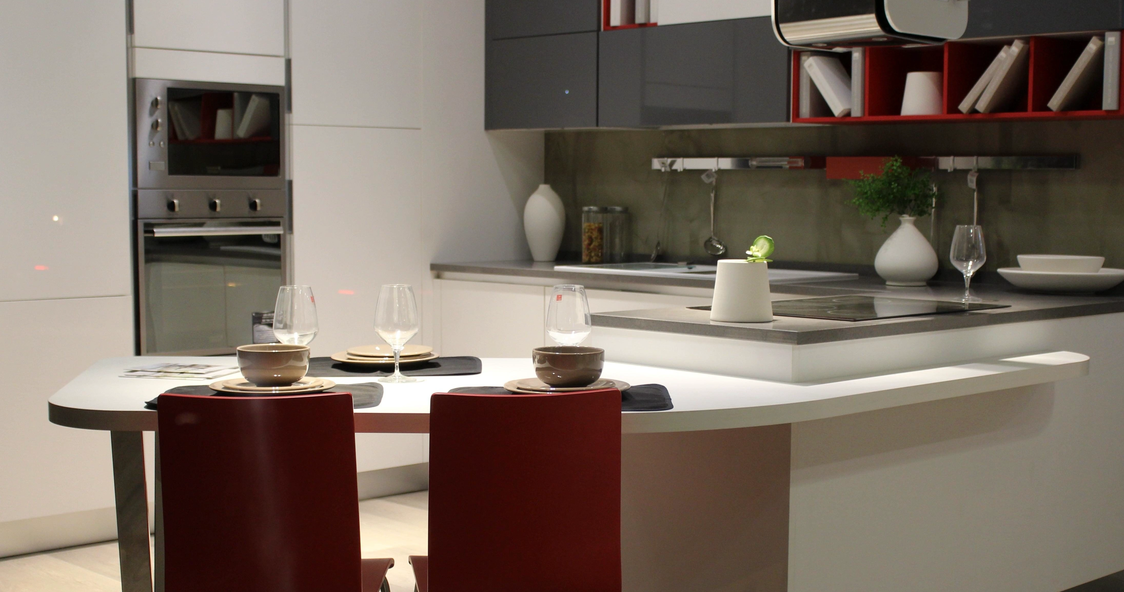 Modern kitchen interior featuring a built-in microwave oven, contemporary cabinetry, and a set dining island with wine glasses.