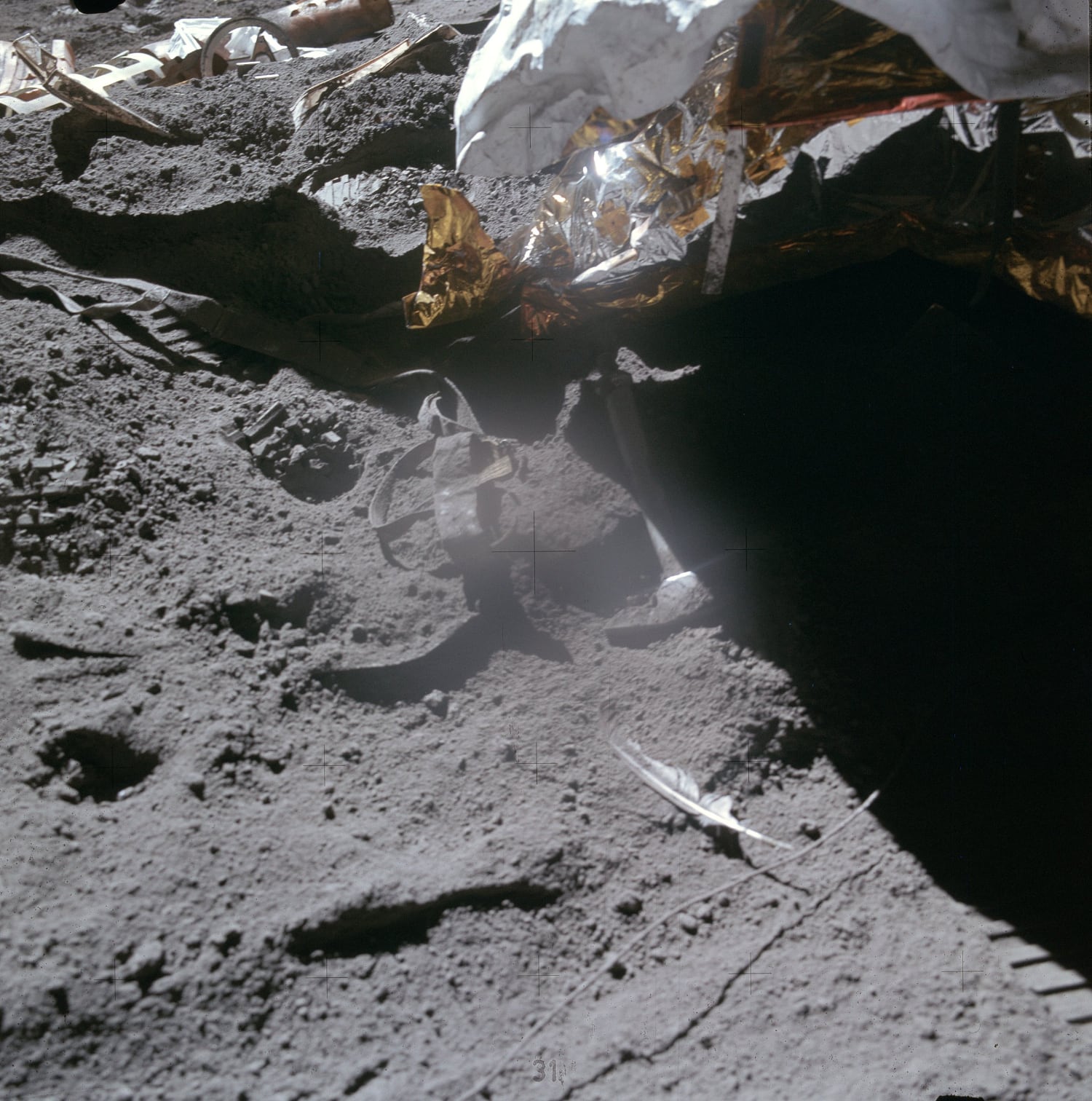 A geological hammer and a white falcon feather lying on the dusty lunar surface after Commander David Scott’s free-fall experiment during Apollo 15, next to the lunar module’s shadow and foil. Photo: NASA